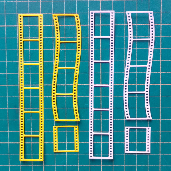 Four plastic film sprocket-edge molds in yellow and white, laid out on a green cutting mat with a grid.