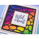 A close-up of a handmade greeting card featuring a black die-cut giraffe pattern over a vibrant rainbow gradient background. A central white square with the cursive text 'Wild AT heart' is layered on top.