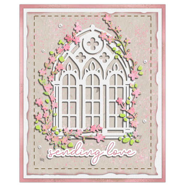 A square handmade card featuring a white arched window design surrounded by pink flowers and green leaves, with the phrase 'sending love' in white script at the bottom. The card has a pink border and is photographed against a plain white background.
