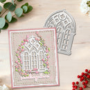 A handmade greeting card with a Gothic-style arched window design, pink cherry blossom vines, and the words 'sending love' in script, shown next to a matching metal die cut on a light wood background with decorative greenery and berries.