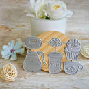 A set of metal cookie cutters shaped like a coffee mug, coffee cup, donut, cupcake, and teacup, displayed on a wooden board with a white flower pot in the background.