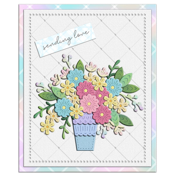 A square handmade-style greeting card featuring a colorful paper flower bouquet in a lavender pot, with a small white tag reading 'sending love' on a pastel patterned border.