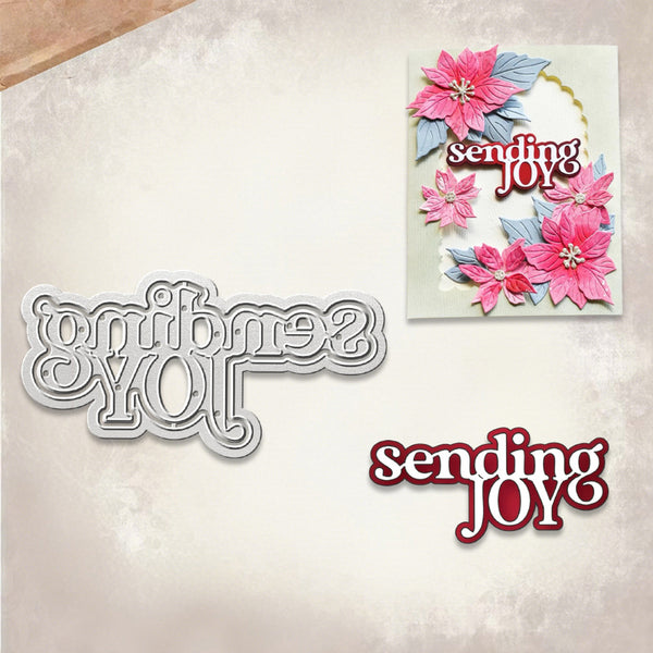 A crafting die set and matching card shown on a textured beige background. The set includes a silver metal die with the phrase 'sending JOY' in decorative lettering and a finished sample card featuring pink poinsettia flowers and the same text.
