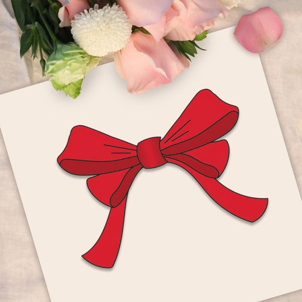 A red ribbon bow illustration or decal on a white card, styled with pink and white flowers at the top.
