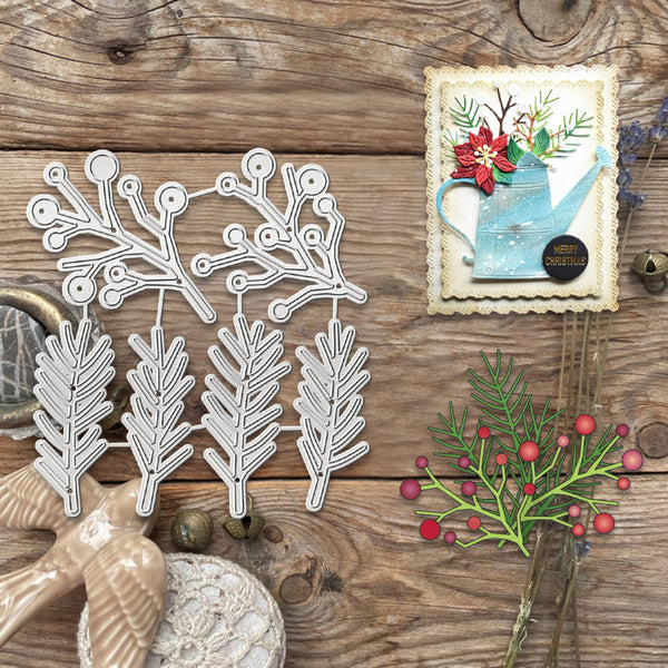 A flat-lay of a white metal die-cutting or crafting template featuring holly and berry branches, displayed on a rustic wooden surface alongside decorative craft props and a handmade card.