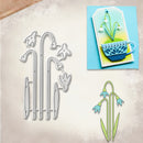 A craft die set featuring silver metal templates for snowdrops and tulips, displayed alongside a finished layered card design and a single layered snowdrop cutout on a textured beige background.
