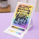 A handmade greeting card set displayed on a lavender table, featuring a large standing card with a rainbow gradient background, black lettering that reads 'FRIEND SENDING love', and a matching flat card with heart-shaped cutouts and a small rainbow 'FRIEND' banner.