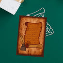 A rectangular decorative card or print featuring an aged parchment scroll with cursive writing, a feather quill, and a wax seal, placed on a dark green background with a white wire hanger behind it.