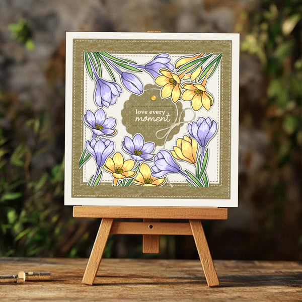 Floral card with 'love every moment' text on a wooden easel against a blurred natural background