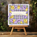 Floral card with yellow and purple flowers on a plaid background, placed on a wooden easel with a blurred natural background.