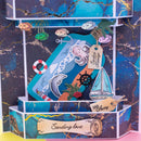 A handmade layered paper gift box with an ocean theme, featuring a blue octopus and dolphin illustration, a sailboat, fish, and gold foil accents on a dark marbled background.