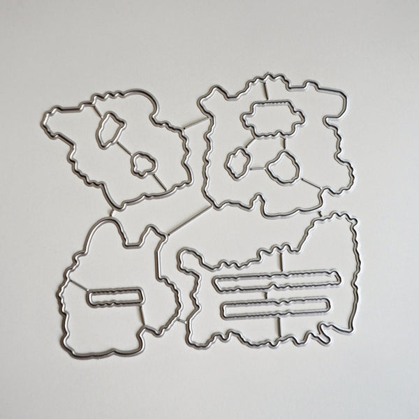 Four metal die-cut craft templates with irregular organic shapes and internal cutout lines, arranged on a plain light background.