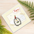 A handmade birthday card featuring a cute hedgehog holding a cupcake, with a speech bubble that reads 'Big birthday energy'. The card is styled on a light wood surface with green fern leaves.
