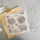 Clear stamp set with autumn-themed designs including pumpkins, flowers, and fall quotes, displayed on a kraft paper sheet next to metal cutting dies on a gray textured background.