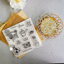 A clear stamp sheet with black line-art illustrations and text, displayed on a kraft paper sheet next to metal cookie cutters on a light gray surface.