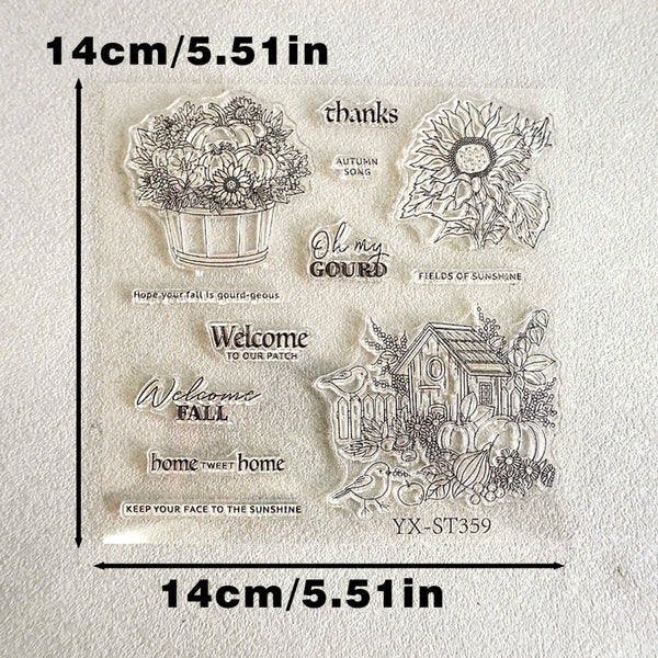 Clear acrylic stamp sheet with autumn-themed designs including pumpkins, sunflowers, a small house, and seasonal phrases, shown on a light textured background with dimension labels of 14cm/5.51in.