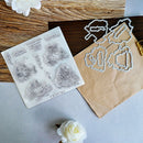 A flat-lay product photo of a clear stamp set and matching metal cutting dies. The stamp sheet on the left features six detailed black ink illustrations of vintage French scenes (such as a windmill and a chaise lounge) with handwritten labels.