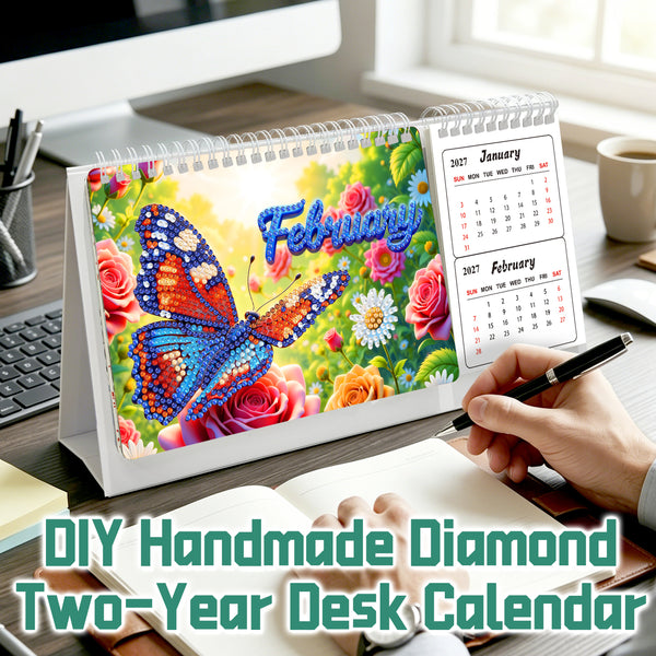 DIY Handmade Diamond Two-Year Desk Calendar shown on a desk with a person's hand writing in an open notebook. The calendar features a colorful diamond-etched design of a blue and orange butterfly on a background of pink roses and green leaves, with 'February' written in blue script.