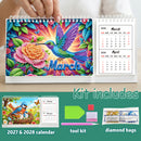 A colorful spiral-bound diamond painting calendar shown open, with a hand holding the top edge. The cover features a vibrant hummingbird and flower design with the word 'March' and monthly calendar pages visible on the right.