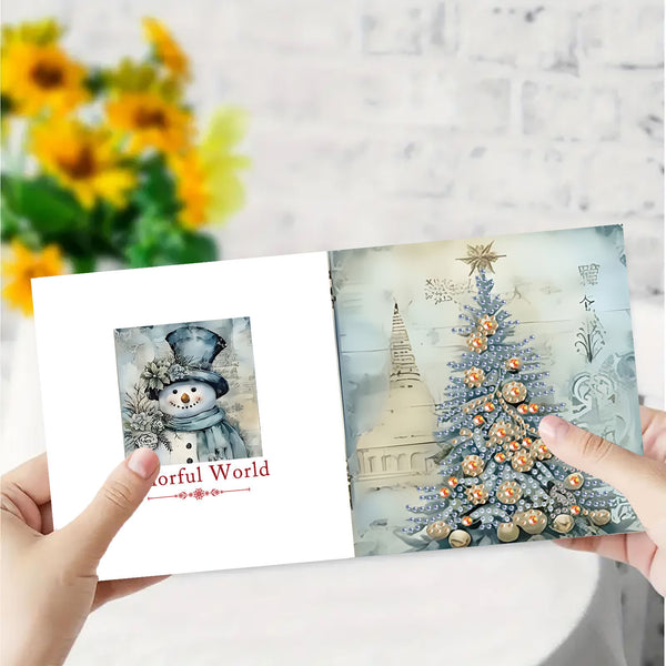 A person holds an open greeting card showing a winter holiday design. The left page features a snowman illustration with the text 'Colorful World,' and the right page shows a decorated Christmas tree with a star topper against a soft, vintage-style background.