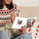 A person sitting indoors holds an open Christmas greeting card. The card shows Santa Claus illustrations and the words 'Colorful World.