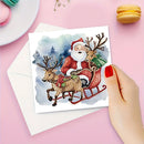 A hand with red nail polish holds a square Christmas greeting card featuring a watercolor-style illustration of Santa Claus in a sleigh pulled by two reindeer, with a white envelope behind it on a pink background.