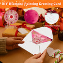 DIY diamond painting greeting card set shown with a white envelope containing a pink glittery diamond painting insert, held by hands over wrapped holiday gifts. Three circular callouts highlight shiny diamond patterns, HD printing, and personalized blessings.
