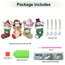 Package contents graphic for a Christmas-themed diamond painting kit, showing four decorated Christmas stockings, four hanging pendants, a pen, clay glue, a green diamond tray, and a multi-colored bead bag under the heading 'Package includes'.
