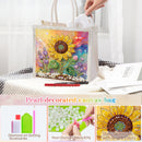 A pearl-decorated canvas tote bag with a colorful sunflower design, shown on a table with a hand holding one handle. The image includes feature callout panels at the bottom detailing diamond art dotting accessories, pearl diamonds, and a close-up of the sunflower embellishment.