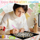 A woman in a white sweater is shown in a decorated room, using a pink diamond painting pen to create a white mandala design on a black canvas. The scene includes various craft supplies like paintbrushes, small decorative items, and a banner at the top that reads 'Enjoy the fun of DIY creation'.