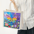 A person wearing a white and gray striped button-up shirt holds a clear plastic tote bag with a colorful diamond painting design of a butterfly and flowers.