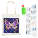 DIY diamond painting canvas tote bag kit featuring a cream canvas bag with a purple and pink glittery butterfly design on a dark blue background, shown alongside paint pens, a green palette, and various colored paint sheets on a white background.