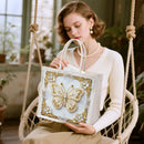 Woman holding a decorative bag with a butterfly design in a home setting