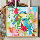 A canvas tote bag with a colorful diamond painting design of two bluebirds, pink flowers, and green leaves, displayed on a wicker chair.