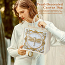 Woman holding a pearl-decorated canvas bag with a dragonfly design.