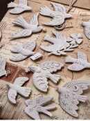 A collection of white ceramic bird-shaped ornaments with detailed engravings, arranged on a vintage-style beige map background.