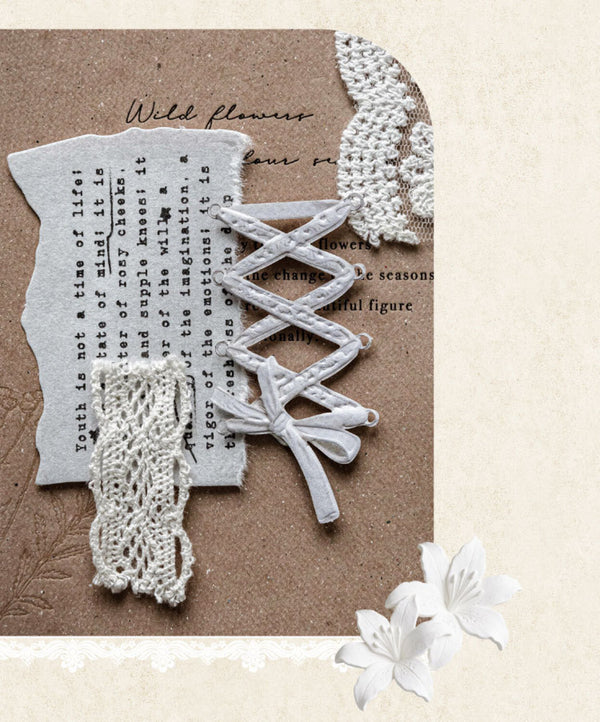 A decorative flat lay featuring white lace trim, a white ribbon bow, and a white paper flower on a textured brown background with torn paper and printed text.