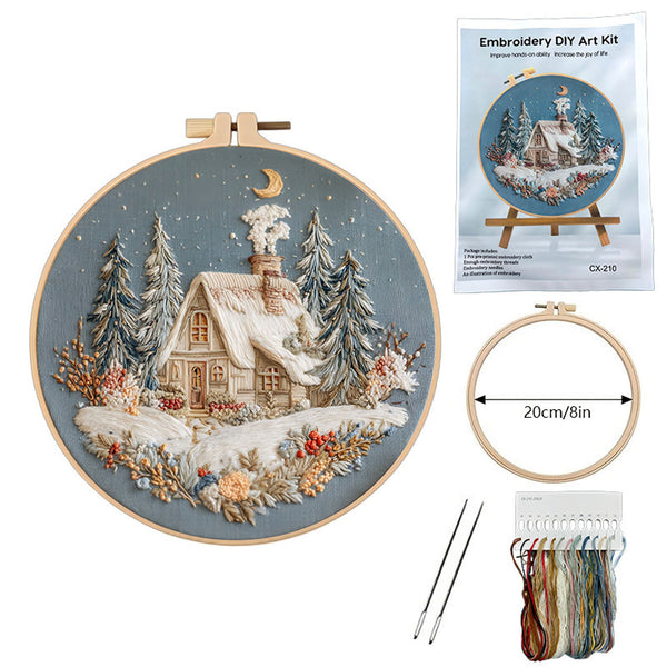 Embroidery DIY art kit with completed design of a snowy cabin, tools, and packaging on a white background.