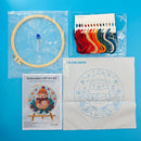 Embroidery DIY art kit with hoop, thread, pattern paper, and color chart on a blue background