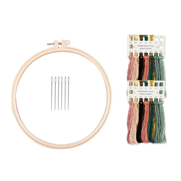Embroidery kit with a large light wood hoop, five metal needles, and a pack of multicolor embroidery floss on a white background.