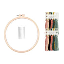 Embroidery kit with a large light wood hoop, five metal needles, and a pack of multicolor embroidery floss on a white background.