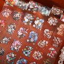 A close-up of decorative adhesive transfer sheets featuring colorful floral and mushroom illustrations on a warm reddish-brown background.