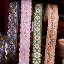 Four decorative ribbons with floral and bow designs on a wooden surface.