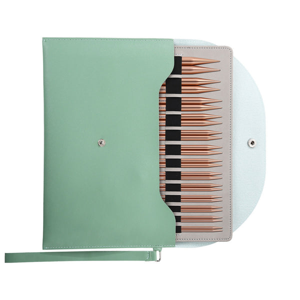 A mint green knitting needle case shown open, revealing a set of knitting needles with rose gold tips and black shafts, on a white background.