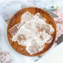Clear jelly-like substance in a wooden bowl on a white surface with floral decorations.
