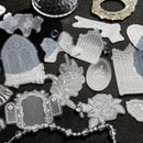 A collection of clear, laser-cut acrylic or glass craft stamps featuring gothic tombstone, rose, and ornate frame designs, arranged on a dark textured background.