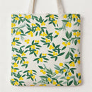 A canvas tote bag with a repeating pattern of green leaves and yellow berries on an off-white background, featuring two cream-colored shoulder straps.