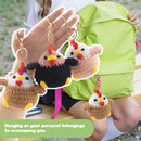Hand holding five crochet chicken keychains with a person in the background.