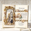 An open decorative book or journal displayed on a white surface, featuring ornate gold floral borders, vintage-style text, and an illustration of a woman with long hair. The background is a pale ornate interior wall with decorative molding.
