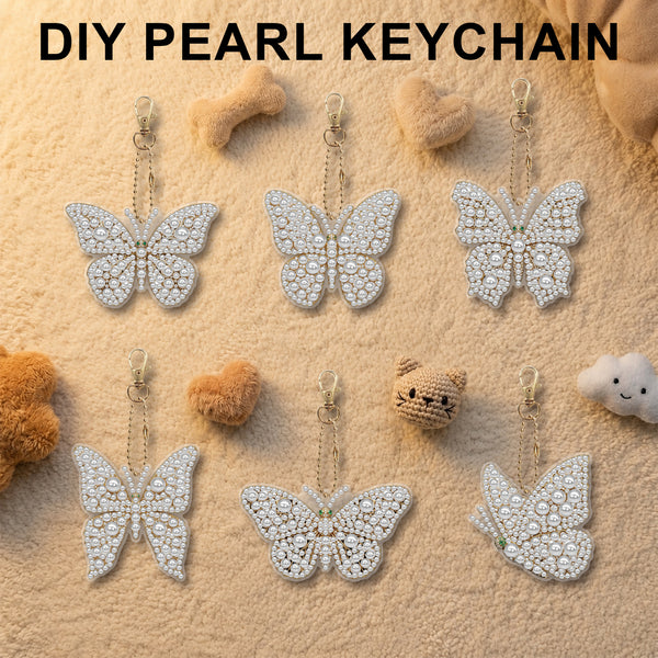 Six pearl-embellished butterfly keychains arranged on a textured beige surface with small decorative props. The text 'DIY PEARL KEYCHAIN' appears at the top.